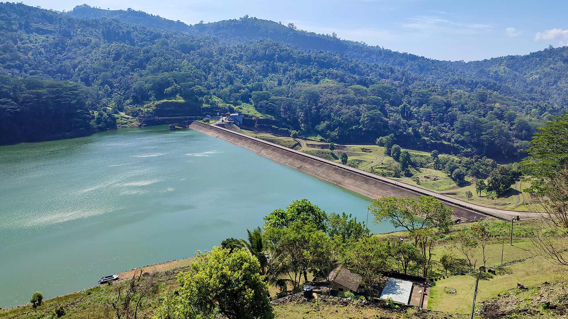 Elevated view over the Kotmale Reservoir dam wall and turquoise water surrounded by forested highland hills